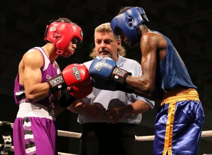 A referee brings two boxers together before the opening bell